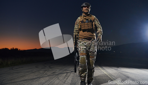 Image of A professional soldier in full military gear striding through the dark night as he embarks on a perilous military mission