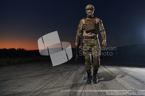 Image of A professional soldier in full military gear striding through the dark night as he embarks on a perilous military mission