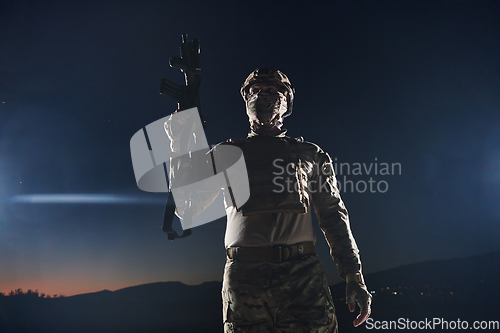 Image of A professional soldier in full military gear striding through the dark night as he embarks on a perilous military mission