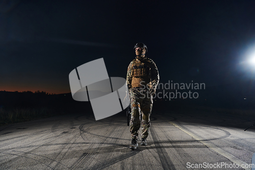 Image of A professional soldier in full military gear striding through the dark night as he embarks on a perilous military mission