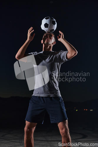 Image of Portrait of a young handsome soccer player man on a street playing with a football ball