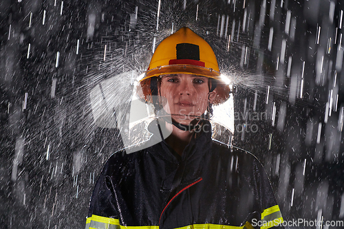 Image of A determined female firefighter in a professional uniform striding through the dangerous, rainy night on a daring rescue mission, showcasing her unwavering bravery and commitment to saving lives.