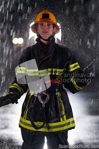 Image of A determined female firefighter in a professional uniform striding through the dangerous, rainy night on a daring rescue mission, showcasing her unwavering bravery and commitment to saving lives.