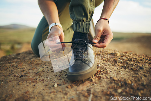 Image of Hands, tie shoes and hiking in nature for travel, training or adventure outdoor. Fitness, sports and person tying laces on sneakers to start workout, walk or running, cardio or workout in countryside