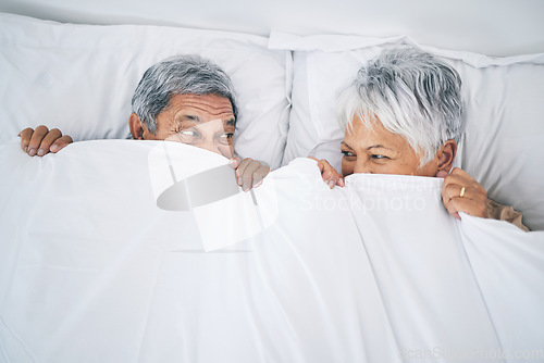 Image of Bed, funny and senior couple covering with a blanket in a bedroom bonding as happiness and playing to enjoy retirement. Happy, goofy and elderly people, man and woman with trust in marriage in a home
