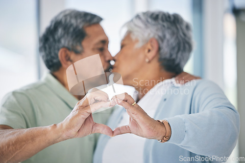 Image of Heart hands, mature couple and kiss with love, kindness and commitment to partner at home. Man, woman and finger shape for sign of support, trust and care of icon of emoji, loyalty and retirement