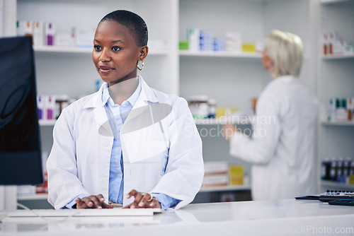 Image of Pharmacist, typing and black woman on computer in pharmacy, drugstore or shop. Wellness, medical professional and African doctor on internet for telehealth email, healthcare and research for medicine