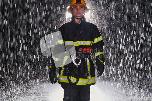 Image of A determined female firefighter in a professional uniform striding through the dangerous, rainy night on a daring rescue mission, showcasing her unwavering bravery and commitment to saving lives.