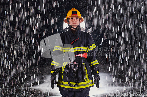 Image of A determined female firefighter in a professional uniform striding through the dangerous, rainy night on a daring rescue mission, showcasing her unwavering bravery and commitment to saving lives.