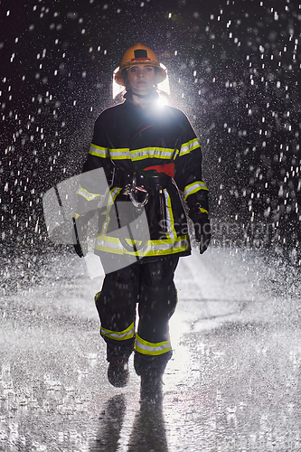 Image of A determined female firefighter in a professional uniform striding through the dangerous, rainy night on a daring rescue mission, showcasing her unwavering bravery and commitment to saving lives.