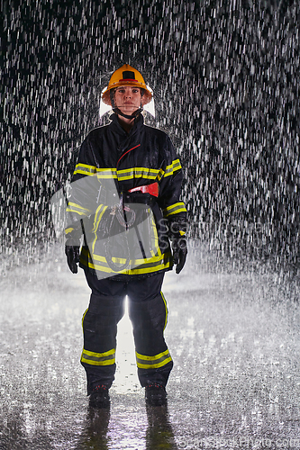 Image of A determined female firefighter in a professional uniform striding through the dangerous, rainy night on a daring rescue mission, showcasing her unwavering bravery and commitment to saving lives.