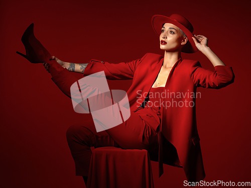 Image of Vision, fashion and a woman on a chair in studio on a red background for elegant or trendy style. Thinking, art and beauty with a young female person sitting in an edgy, classy or unique suit