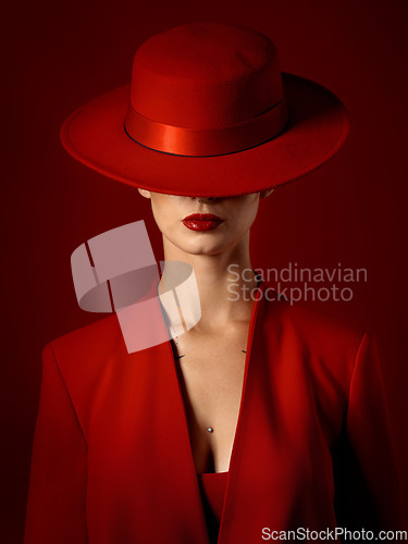 Image of Beauty, fashion and woman in a vintage suit with hat in studio with retro, style and edgy, confident or creative pose on red background. Mystery character, model and girl with power or aesthetic