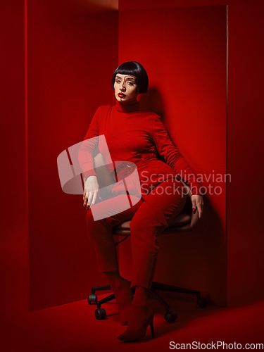 Image of Beauty, fashion and woman on a chair with red background in studio for elegant, chic or trendy style. Aesthetic, art and confident with edgy or classy young person in unique clothes or suit at board