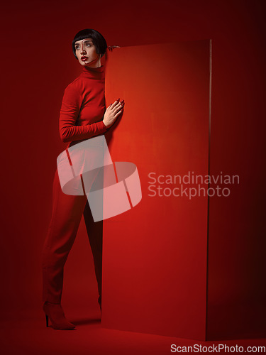 Image of Beauty, fashion and a model woman on red background in studio for elegant, chic or trendy style. Aesthetic, art and confident with an edgy or classy young person in a unique clothes or suit at board