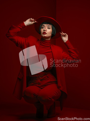 Image of Woman, fashion and beauty with red aesthetic, makeup with art deco and vintage hat isolated on studio background. Retro style, female model with serious expression and cosmetics, attractive and bold