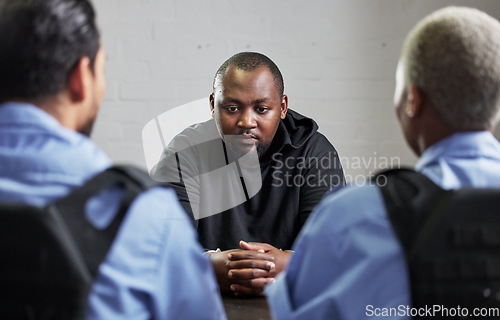 Image of Police, criminal and handcuffs for interrogation, questions or justice in fraud, scam or crime. Law enforcement officers talking to prisoner, gangster or thief in arrest for robbery in prison or jail