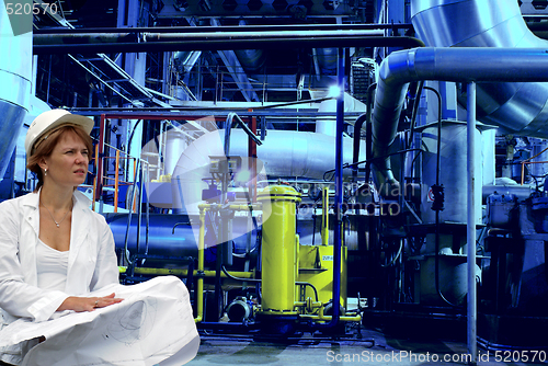 Image of woman engineer, equipment, cables and piping as found inside of 