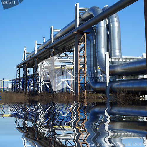 Image of industrial pipelines on pipe-bridge against blue sky  with refle