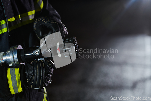 Image of Firefighter using a water hose to eliminate a fire hazard. Team of firemen in the dangerous rescue mission.