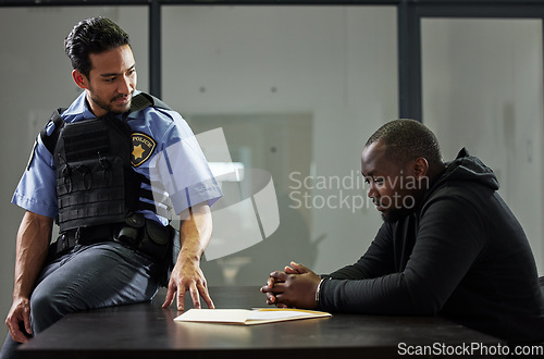 Image of Police, interrogation and black man, suspect or criminal investigation for crime at station. African person with handcuffs at table, detective and people in discussion, interview and law questions.