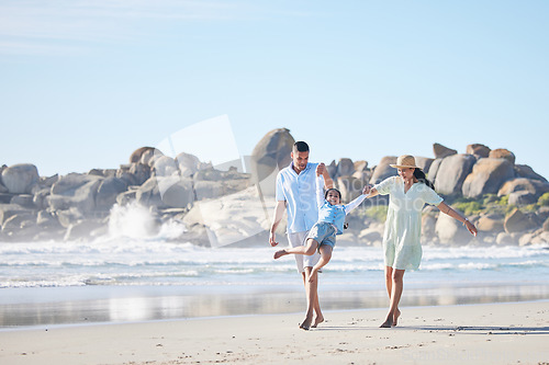 Image of Family, parents and swinging a child at the beach for fun, adventure and play on holiday. A happy woman, man and young kid walking on sand and holding hands on vacation at ocean, nature or outdoor