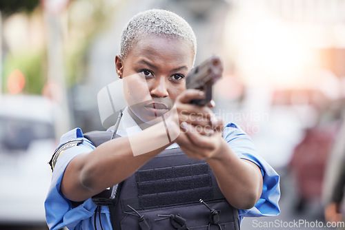 Image of Gun, serious and female police officer in the city for an arrest to stop crime in a street. Upset, young and African woman security guard with pistol for safety, authority and law enforcement in town