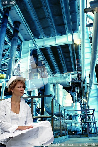 Image of woman engineer, equipment, cables and piping as found inside of 