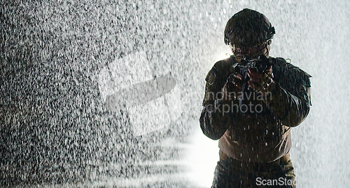 Image of Army soldier in Combat Uniforms with an assault rifle, plate carrier and combat helmet going on a dangerous mission on a rainy night.