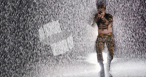 Image of Army soldier in Combat Uniforms with an assault rifle, plate carrier and combat helmet going on a dangerous mission on a rainy night.