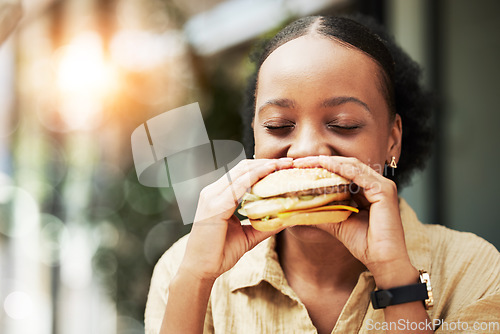 Image of Happy, fast food and black woman eating a sandwich in an outdoor restaurant as a lunch meal craving deal. Breakfast, burger and young female person or customer enjoying a tasty unhealthy snack