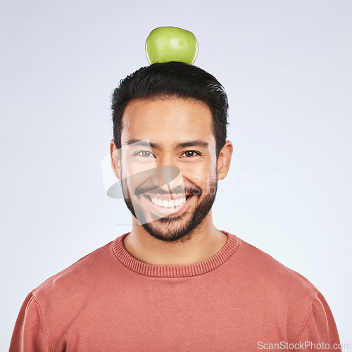 Image of Portrait, apple head balance and man smile for weight loss diet, healthy snack or body nutrition vitamins. Eating food, nutritionist fruit and studio face of hungry Asian person on white background