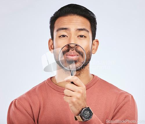 Image of Mouth, portrait of a man with a magnifying glass in hand on a white studio background for investigation. Face of Asian person or model with a magnifier to show lips or zoom for inspection or emoji