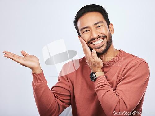 Image of Hand pointing, smile and portrait of asian man in studio with mockup, promotion or news on a white background. Happy, face and male person with platform for menu, open palm or sale announcement