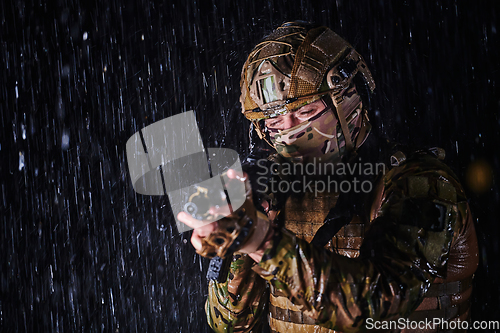 Image of Army soldier in Combat Uniforms with an assault rifle, plate carrier and combat helmet going on a dangerous mission on a rainy night.