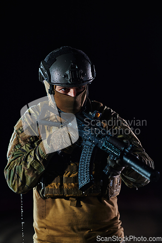 Image of A professional soldier in full military gear striding through the dark night as he embarks on a perilous military mission