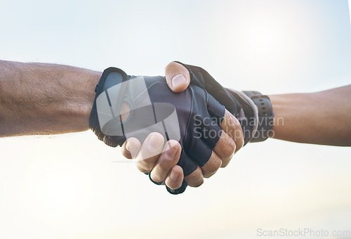 Image of Teamwork, cycling and sports men shaking hands outdoor together against a sky background with flare. Handshake, fitness and partnership with a cyclist team saying thank you during a cardio workout