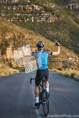 Image of Man, cycling and celebration with back on mountain road, strong arm muscle or fist in air for winning. Winner athlete, bicycle or achievement for health, workout or training for performance in nature