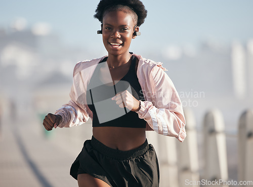 Image of Portrait, running and black woman outdoor with earphones for audio, radio music and podcast. Sports, fitness and happy African athlete training, workout and exercise for health, wellness and cardio