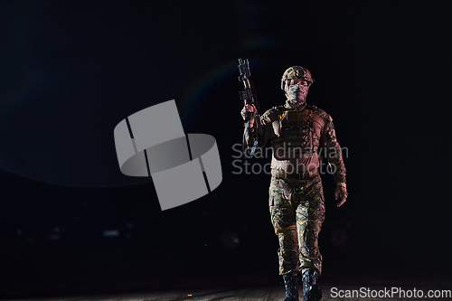 Image of A professional soldier in full military gear striding through the dark night as he embarks on a perilous military mission