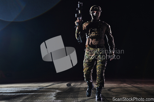 Image of A professional soldier in full military gear striding through the dark night as he embarks on a perilous military mission