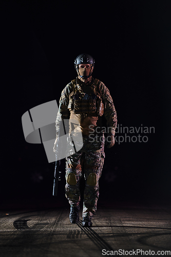 Image of A professional soldier in full military gear striding through the dark night as he embarks on a perilous military mission