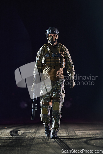 Image of A professional soldier in full military gear striding through the dark night as he embarks on a perilous military mission