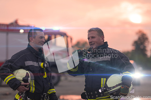 Image of Fireman using walkie talkie at car traffic rescue action fire truck and fireman's team in background.