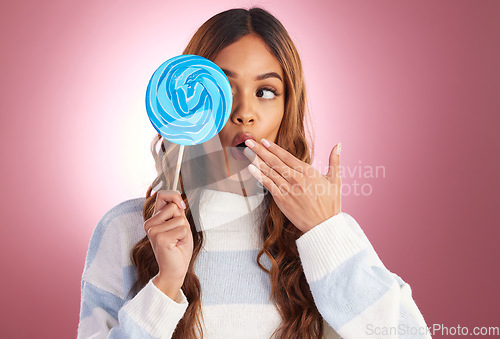 Image of Woman, lollipop and eye with surprise in studio with hand on mouth for shock, wow and amazed by backdrop. Young excited girl, model and candy on stick by gradient background to cheat diet with sweets