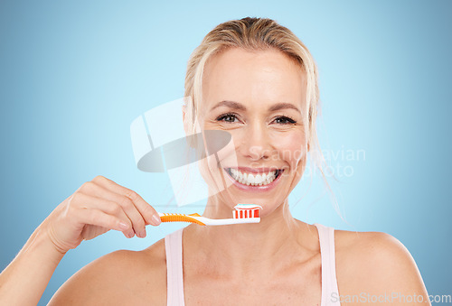 Image of Woman, toothbrush and smile with teeth for dental care, dentist or oral hygiene against a blue studio background. Portrait of happy mature female smiling in satisfaction for mouth or gum treatment