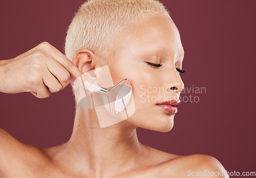 Image of Beauty, skincare and woman with facial roller, cosmetics and luxury salon treatment on studio background. Makeup, female and lady with confidence, rose quartz and wellness with heathy and smooth soft