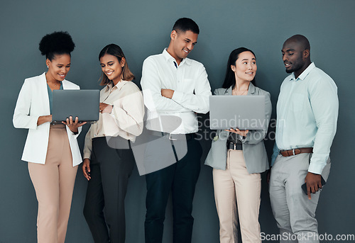 Image of Business people, group and laptop by wall background in office, corporate startup and coaching with happiness. Young executive team, diversity and mentor with men, women and computer for learning