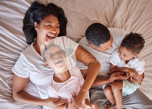 Image of Top view, love and black family in bedroom, playful and cheerful on weekend break, quality time or happiness. African American mother, father or children on bed, joyful or relax with support or laugh