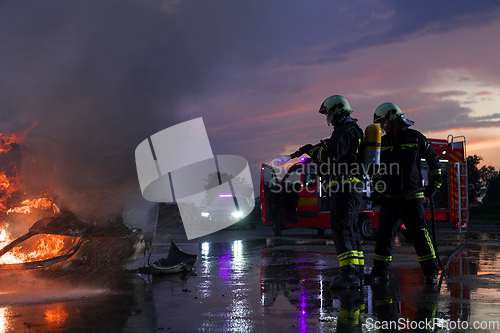 Image of Firefighters fight the fire flame to control fire not to spreading out. Firefighter industrial and public safety concept. Traffic or car accident rescue and help action.